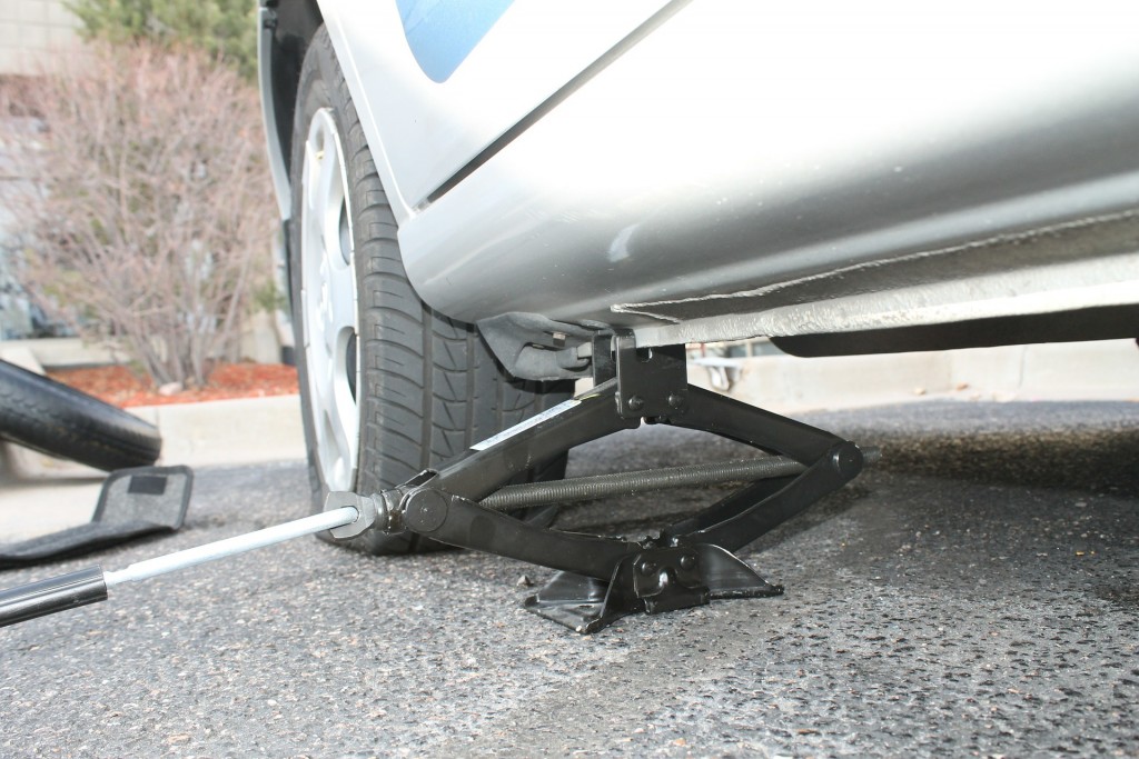 Read your owner's manual for specific instructions on where to place the jack, then turn to raise the vehicle.